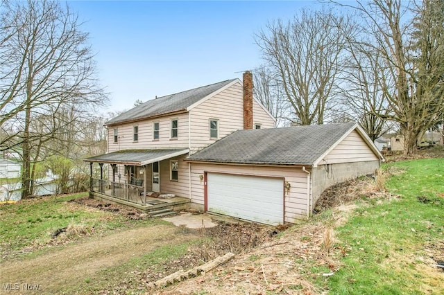 view of side of home with a porch, dirt driveway, an attached garage, and a chimney