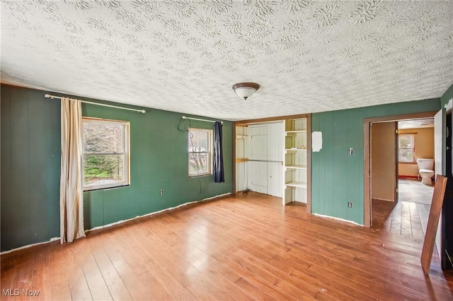 unfurnished bedroom featuring baseboards, hardwood / wood-style flooring, and a textured ceiling