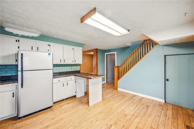 kitchen featuring tasteful backsplash, freestanding refrigerator, dark countertops, and white cabinetry