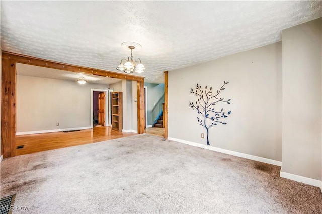 spare room featuring visible vents, baseboards, carpet, a textured ceiling, and stairs