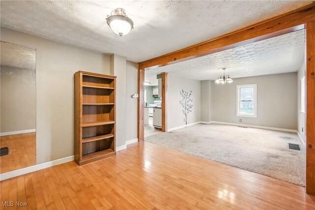 unfurnished room featuring a textured ceiling, an inviting chandelier, baseboards, and visible vents