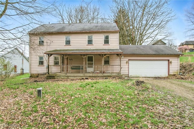view of front of property featuring an attached garage, driveway, a front yard, and covered porch
