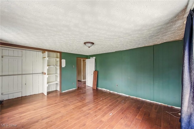 unfurnished bedroom with wood-type flooring, baseboards, and a textured ceiling