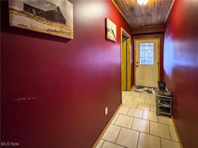 doorway featuring wooden ceiling, light tile patterned flooring, and baseboards