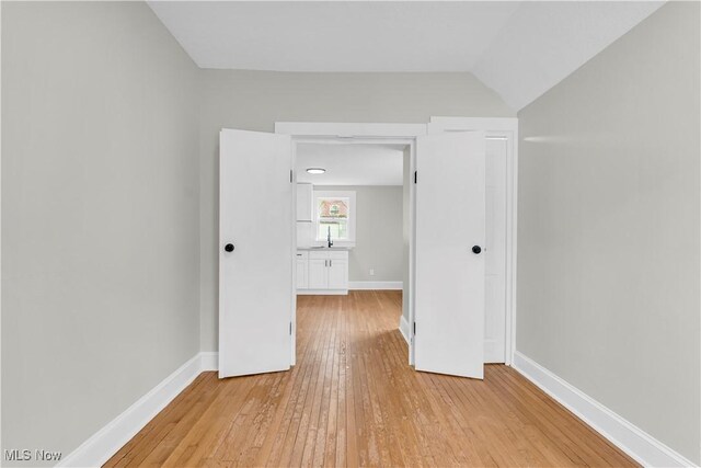 1244 W 69th St, Cleveland, OH 44102 - empty room featuring a sink, light wood-type flooring, baseboards, and lofted ceiling