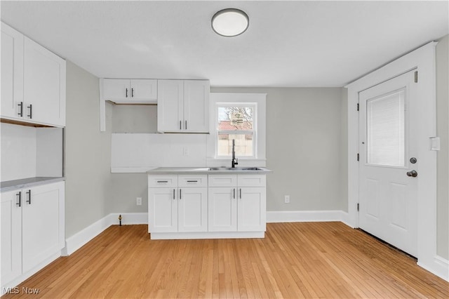 1244 W 69th St, Cleveland, OH 44102 - kitchen with light wood-style flooring, a sink, white cabinetry, and baseboards