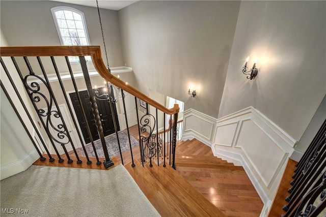 staircase featuring wood finished floors, wainscoting, and a decorative wall