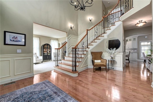 foyer featuring a decorative wall, light wood finished floors, a towering ceiling, and stairs