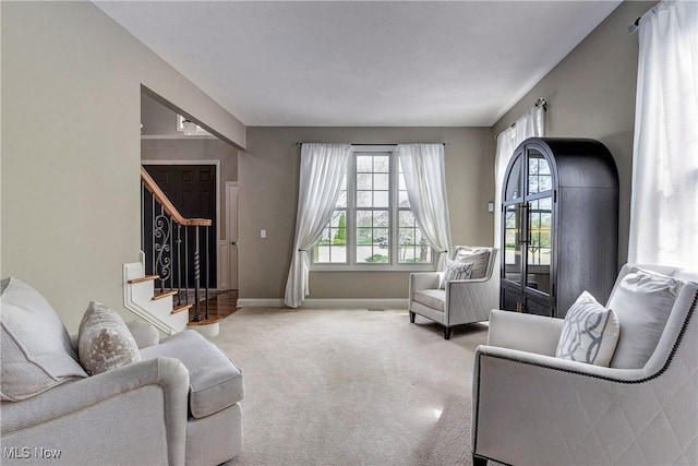 carpeted living room featuring baseboards and stairs