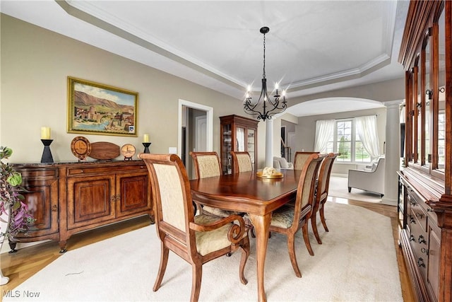 dining area with crown molding, decorative columns, arched walkways, a chandelier, and a raised ceiling