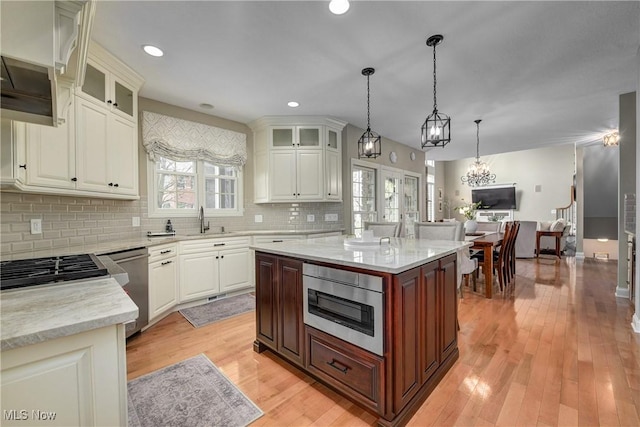 kitchen with stainless steel dishwasher, tasteful backsplash, light stone counters, a sink, and built in microwave