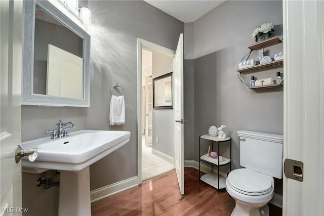 bathroom with toilet, wood finished floors, a sink, and baseboards