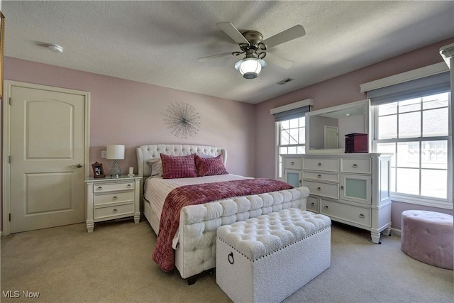 bedroom with carpet floors, ceiling fan, visible vents, and a textured ceiling