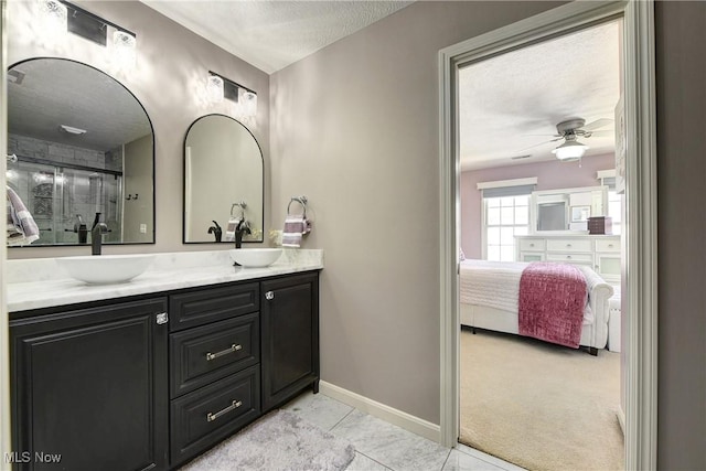 bathroom with a textured ceiling, ceiling fan, a sink, and connected bathroom