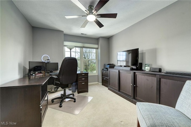 home office with visible vents, ceiling fan, light colored carpet, and baseboards