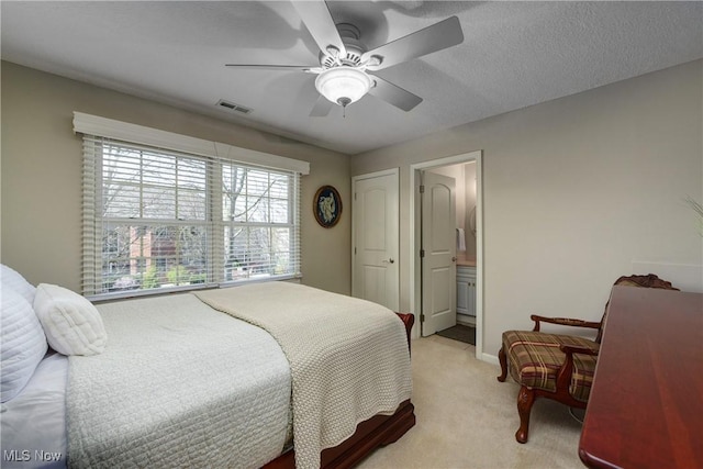 bedroom with visible vents, ensuite bathroom, baseboards, ceiling fan, and light colored carpet