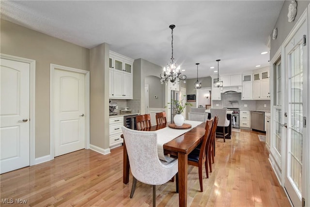 dining area with light wood-style flooring, a notable chandelier, baseboards, and recessed lighting