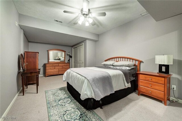 bedroom with a closet, light colored carpet, a ceiling fan, visible vents, and baseboards