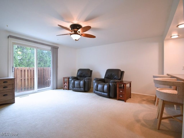 living area with light carpet and ceiling fan