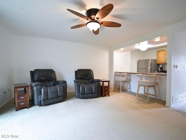 sitting room with visible vents, light colored carpet, and ceiling fan