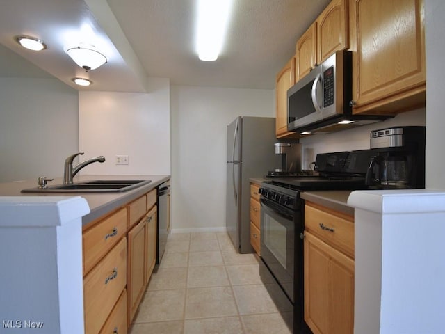 kitchen featuring light brown cabinets, baseboards, light tile patterned flooring, stainless steel appliances, and a sink