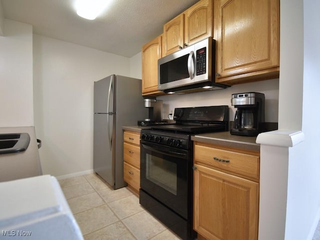 kitchen featuring light tile patterned floors, baseboards, and appliances with stainless steel finishes