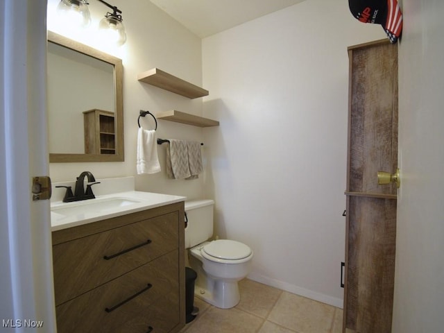 bathroom featuring toilet, tile patterned flooring, baseboards, and vanity