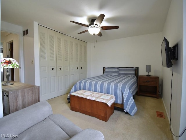 bedroom with light carpet, a closet, a ceiling fan, and visible vents