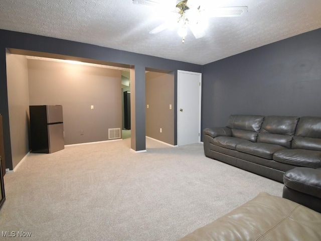 living room featuring baseboards, a textured ceiling, a ceiling fan, carpet floors, and visible vents