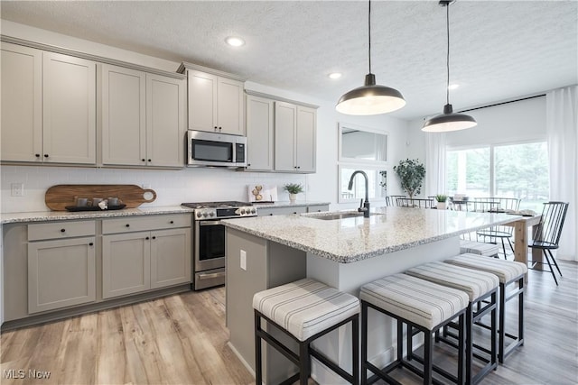 kitchen with stainless steel appliances, a textured ceiling, a sink, and gray cabinets