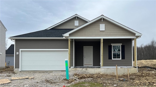 view of front of property with an attached garage, roof with shingles, and covered porch