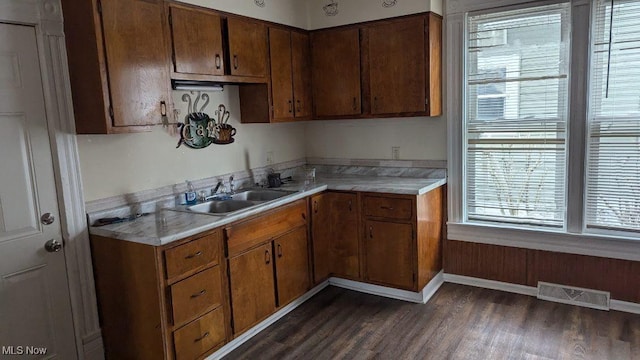 kitchen featuring a sink, visible vents, light countertops, and dark wood finished floors