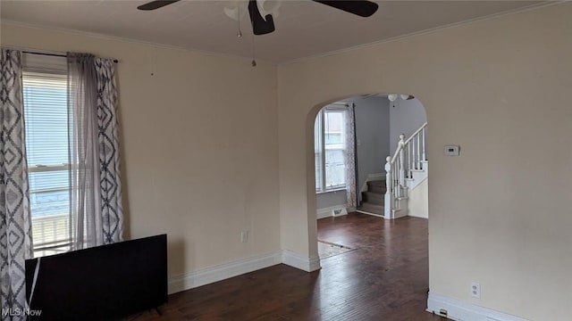 unfurnished room featuring arched walkways, baseboards, wood finished floors, and ceiling fan