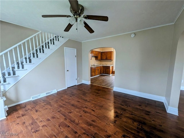 1636 W 8th St, Ashtabula, OH 44004 - unfurnished living room featuring arched walkways, dark wood finished floors, baseboards, ceiling fan, and crown molding