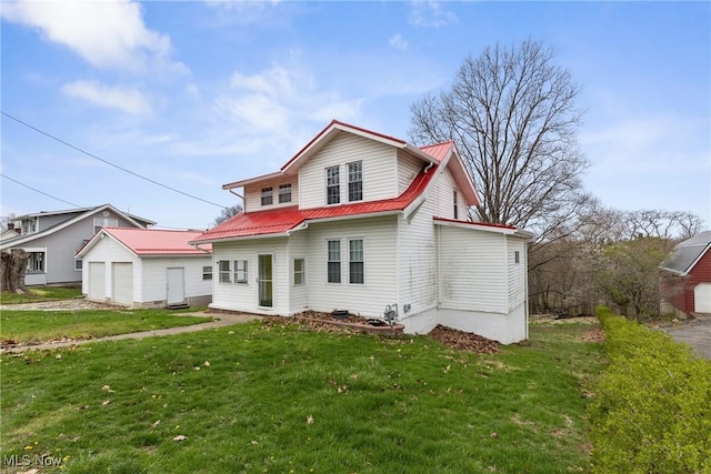 rear view of property featuring a yard, a detached garage, an outdoor structure, and metal roof