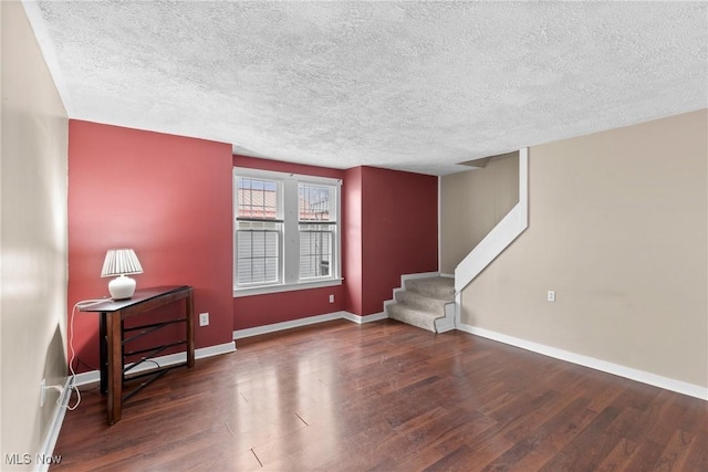 interior space with a textured ceiling, wood finished floors, and stairs