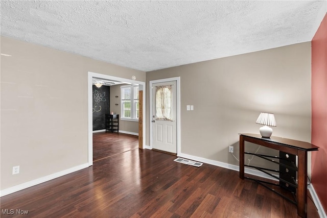 entrance foyer with visible vents, baseboards, a textured ceiling, and wood finished floors