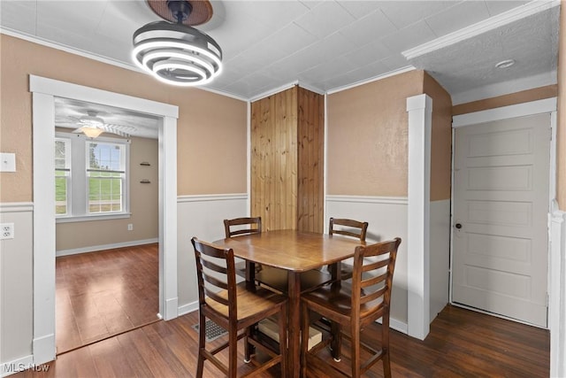 dining area with a ceiling fan, crown molding, wainscoting, wood finished floors, and wood walls
