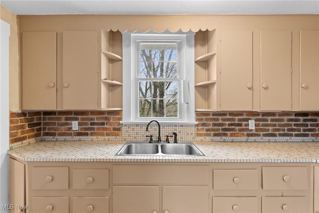 kitchen with a sink, backsplash, light countertops, and open shelves