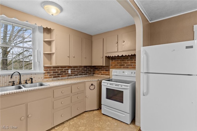 kitchen with white appliances, light countertops, cream cabinets, backsplash, and a sink