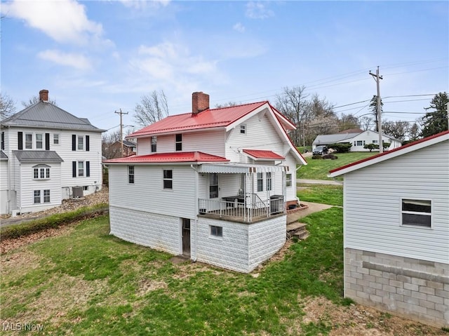 rear view of property with a yard, metal roof, and a chimney