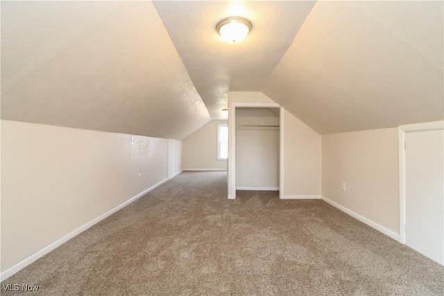 additional living space with carpet flooring, baseboards, and vaulted ceiling