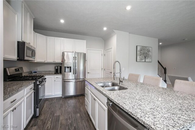 kitchen with light stone counters, stainless steel appliances, dark wood finished floors, and a sink