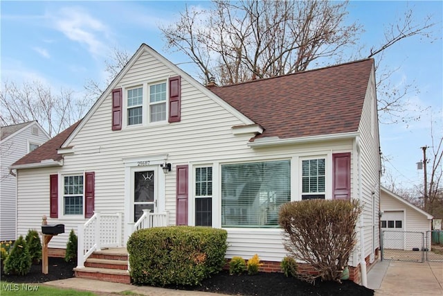 view of front of house with a shingled roof and a detached garage
