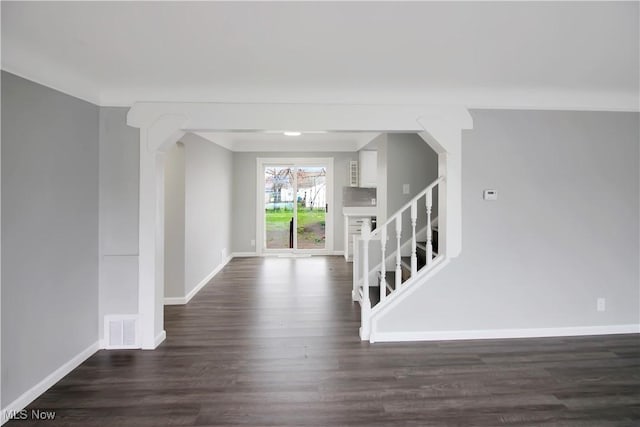 entrance foyer featuring arched walkways, dark wood-style flooring, baseboards, and visible vents