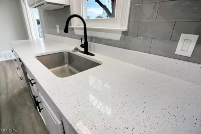details with light stone countertops, a sink, and wood finished floors
