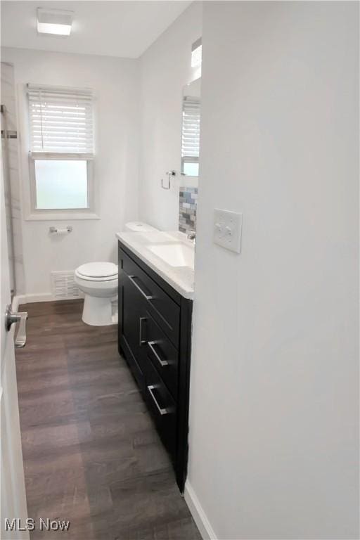bathroom with visible vents, baseboards, toilet, vanity, and wood finished floors