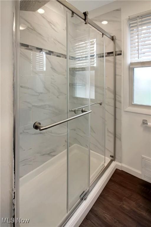 bathroom featuring a marble finish shower, visible vents, baseboards, and wood finished floors