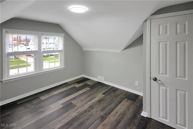 bonus room featuring dark wood-style flooring, visible vents, baseboards, and lofted ceiling