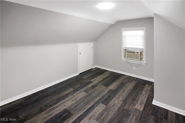 additional living space with baseboards, cooling unit, vaulted ceiling, and dark wood finished floors